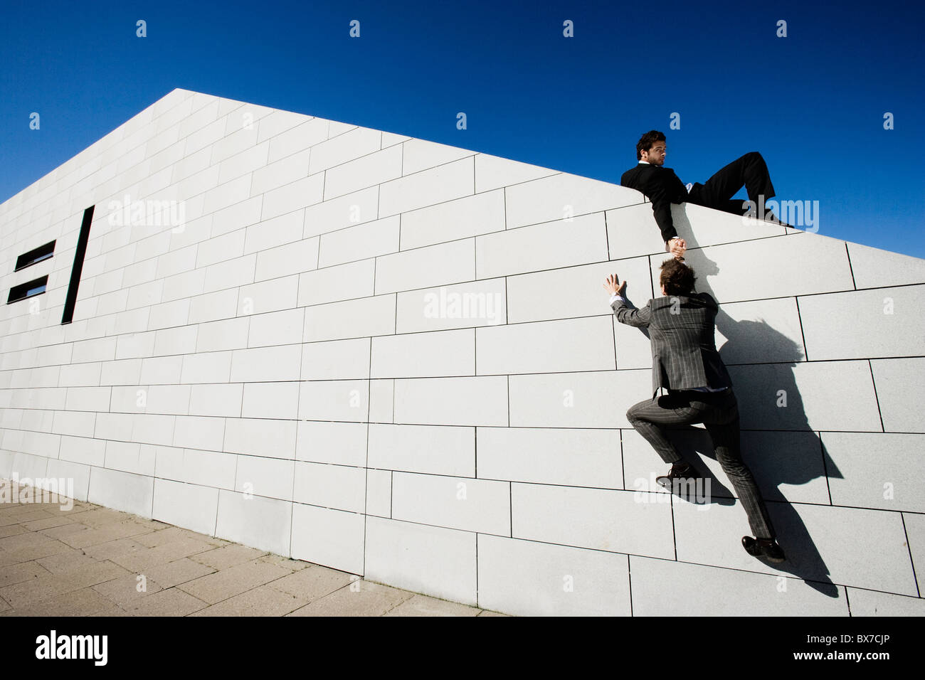 Menschen anderen Menschen helfen, über Mauer Stockfoto