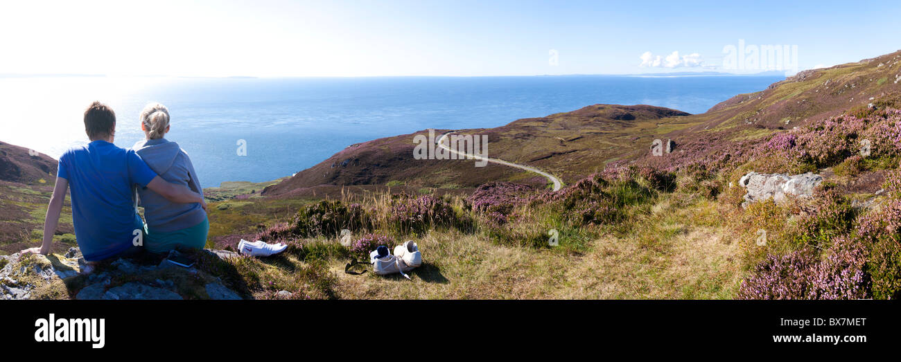 Ein junges Paar genießt die Aussicht von der Mull of Kintyre, Argyll & Bute, Schottland, Großbritannien - Islay und Jura sind im Hintergrund zu sehen Stockfoto