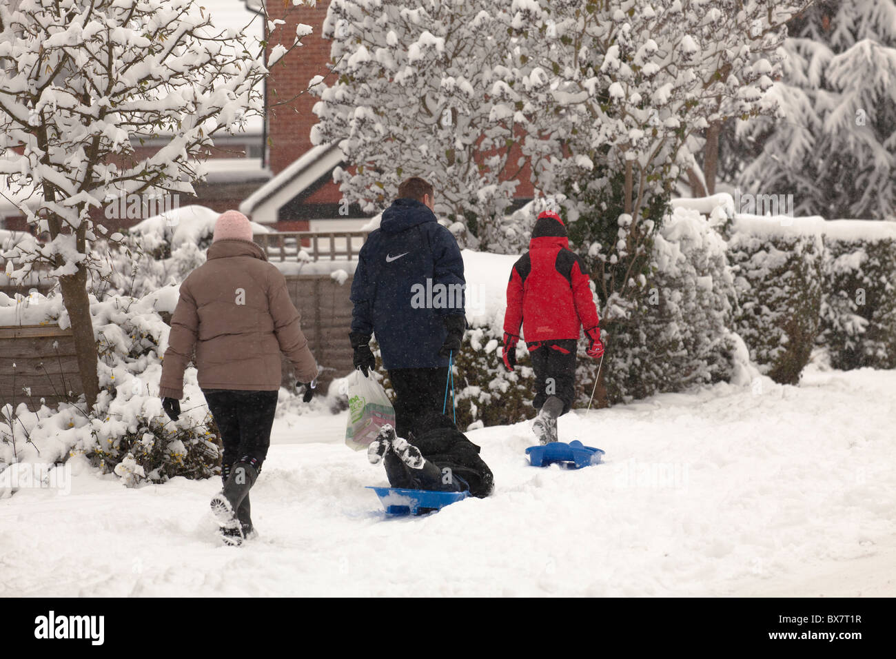 Familie gehen auf Vorort Straße im Schnee mit Schlitten Stockfoto