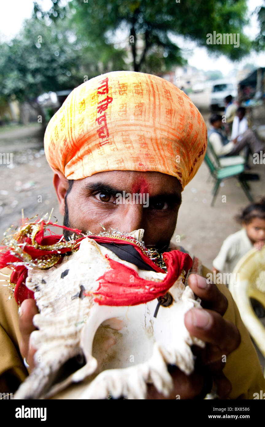 Ein indischer Sadhu weht eine Muschel (Cone Shell) während einer hinduistischen Zeremonie. Stockfoto