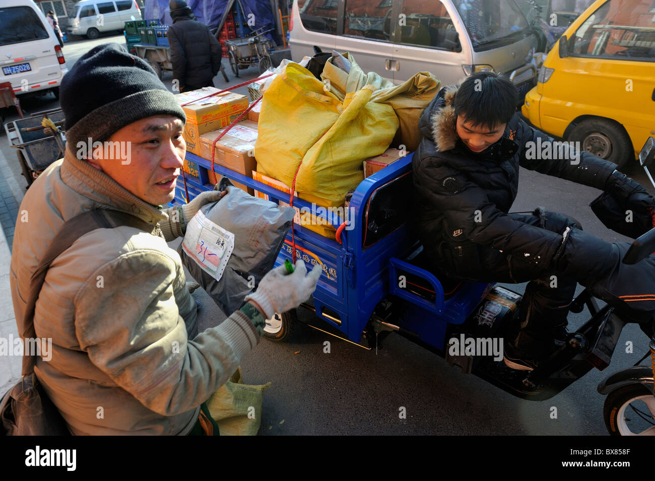 Kuriere des lokalen Shentong Express erhalten Pakete auf einem motor Dreirad in einem Umspannwerk in Peking, China geliefert werden. 2010 Stockfoto