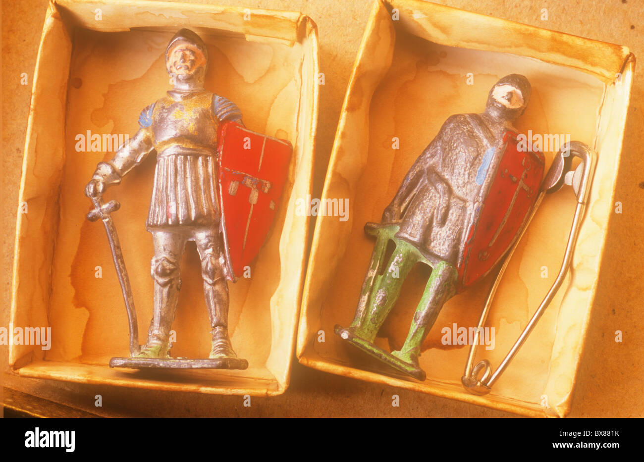 Nahaufnahme von zwei zerkratzt Metall Blei-Modelle der Ritter in Rüstung mit Schwert und Schild in gefärbten Kärtchen Tabletts liegen Stockfoto