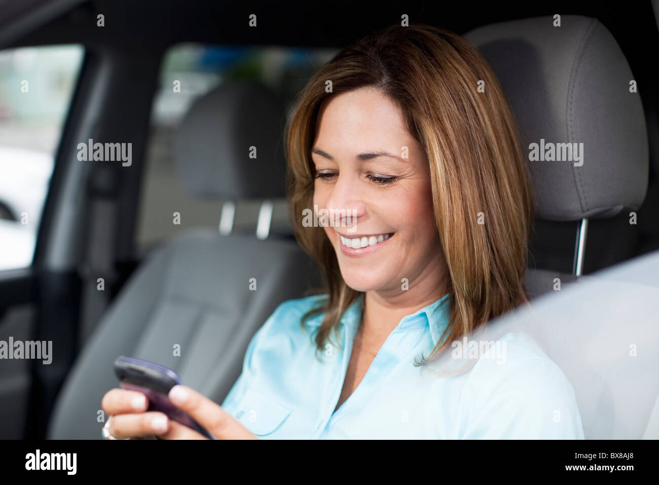 Frau im Auto Check-Handy Stockfoto