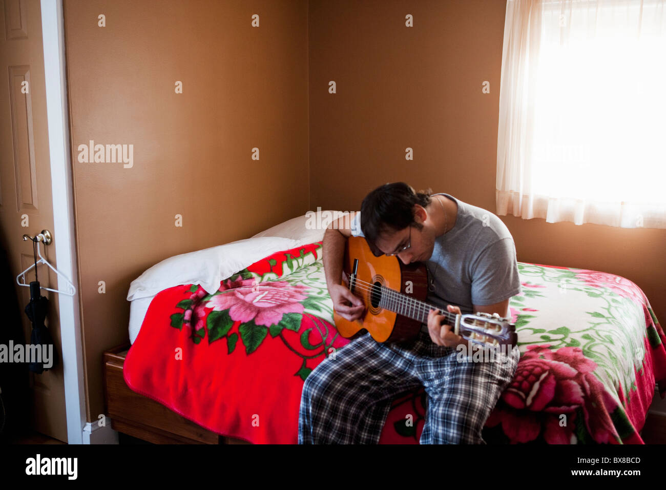 Mann Gitarre spielen auf Bett Stockfoto