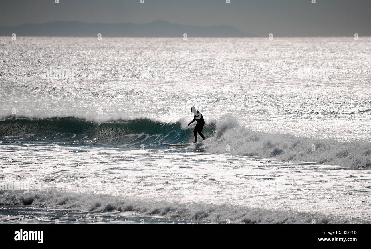 Ein Surfer auf einer Welle aus der Pacific Coast, Kalifornien, Hawaii, USA. Wellen und einer schönen Bergkette. Stockfoto