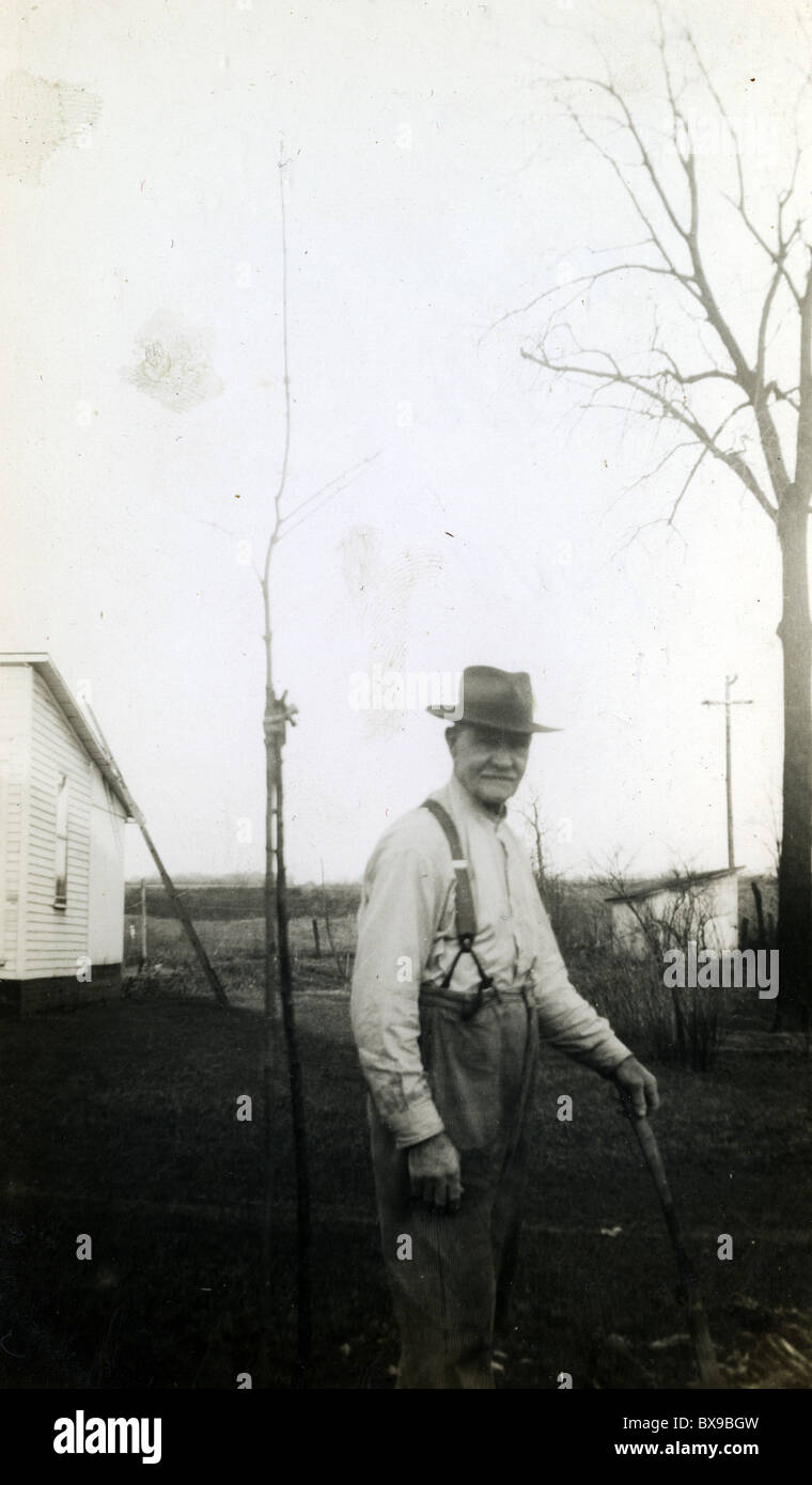 Alter Mann mit Stock auf Bauernhof Bauer ältere männliche Mode Strapse Stockfoto
