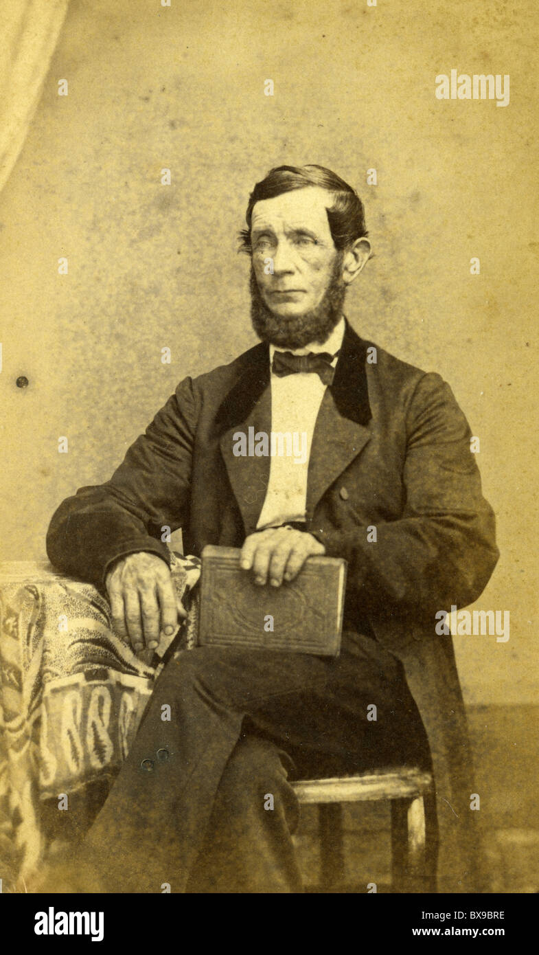 Mann trägt schwarzen Mantel fotografieren der 1860er Jahre Mode Fliege männlichen sitzenden Porträt Americana schwarz / weiß Stockfoto