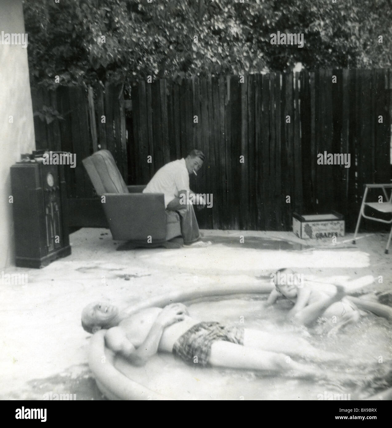 Vater und Sohn Entspannung in Schwimmbad Mann sitzt Sessel tube Radio Amerika der 1950er Jahre tragbare Hinterhoflache heißen Tag Sommer Stockfoto