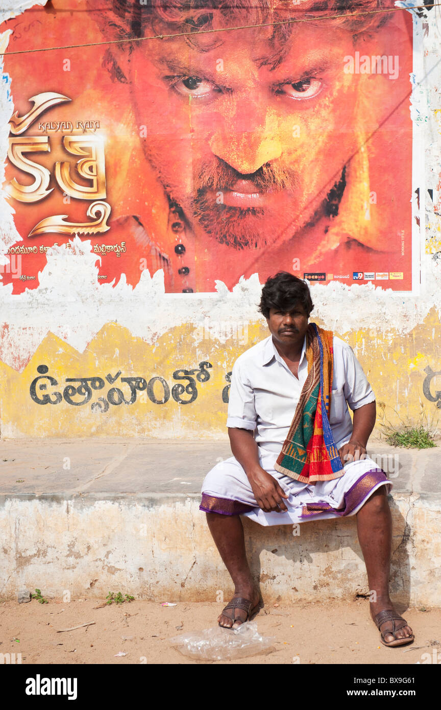 South Indian Mann vor eine schäbige alte Filmplakat sitzend. Andhra Pradesh, Indien Stockfoto