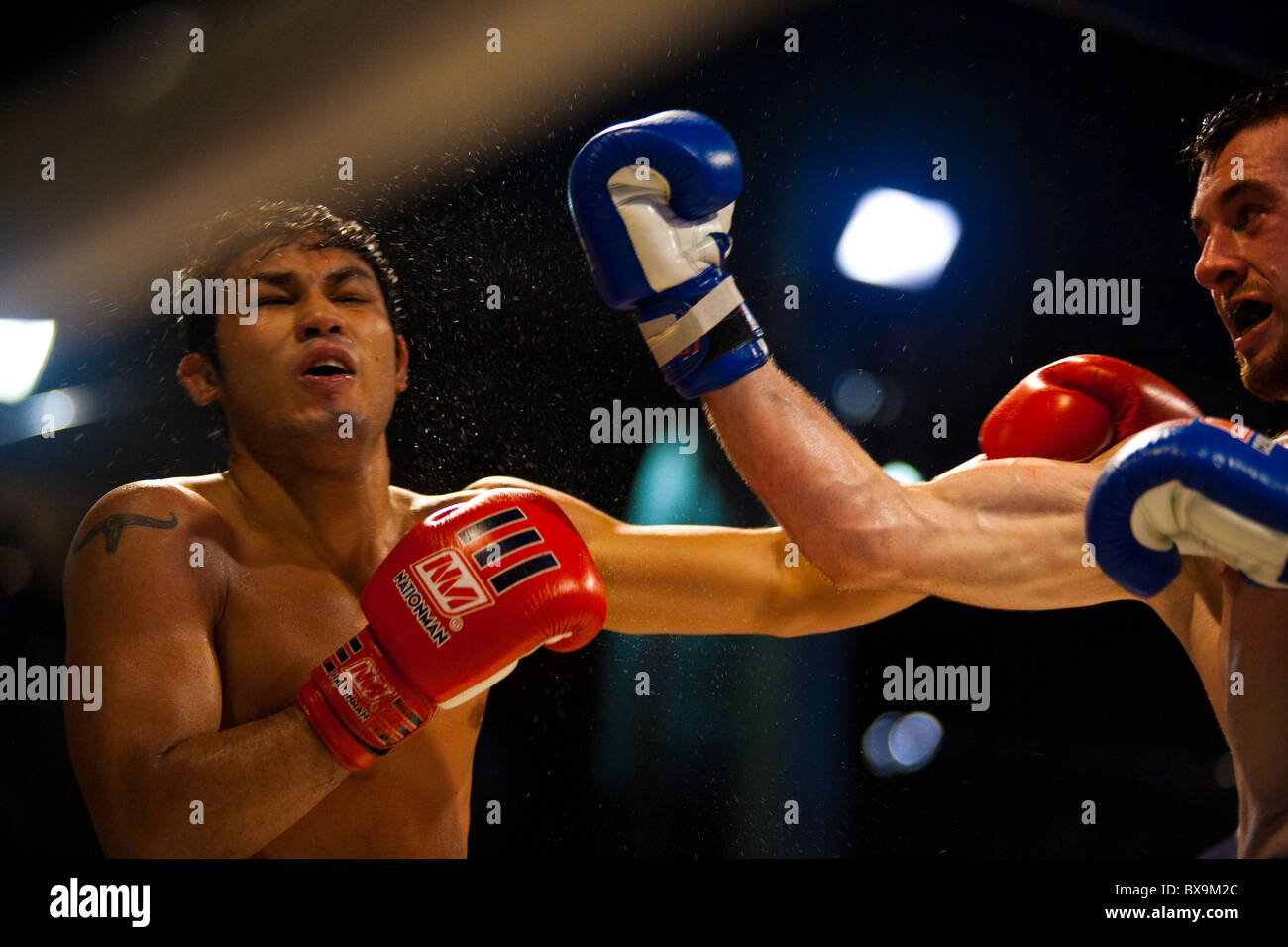 Kaukasische Kämpfer Landung Aufwärtshaken zum Gesicht des asiatischen Thai-Boxer, Schweiß während outdoor Amateur Muay thai kickboxen Spiel fliegen Stockfoto