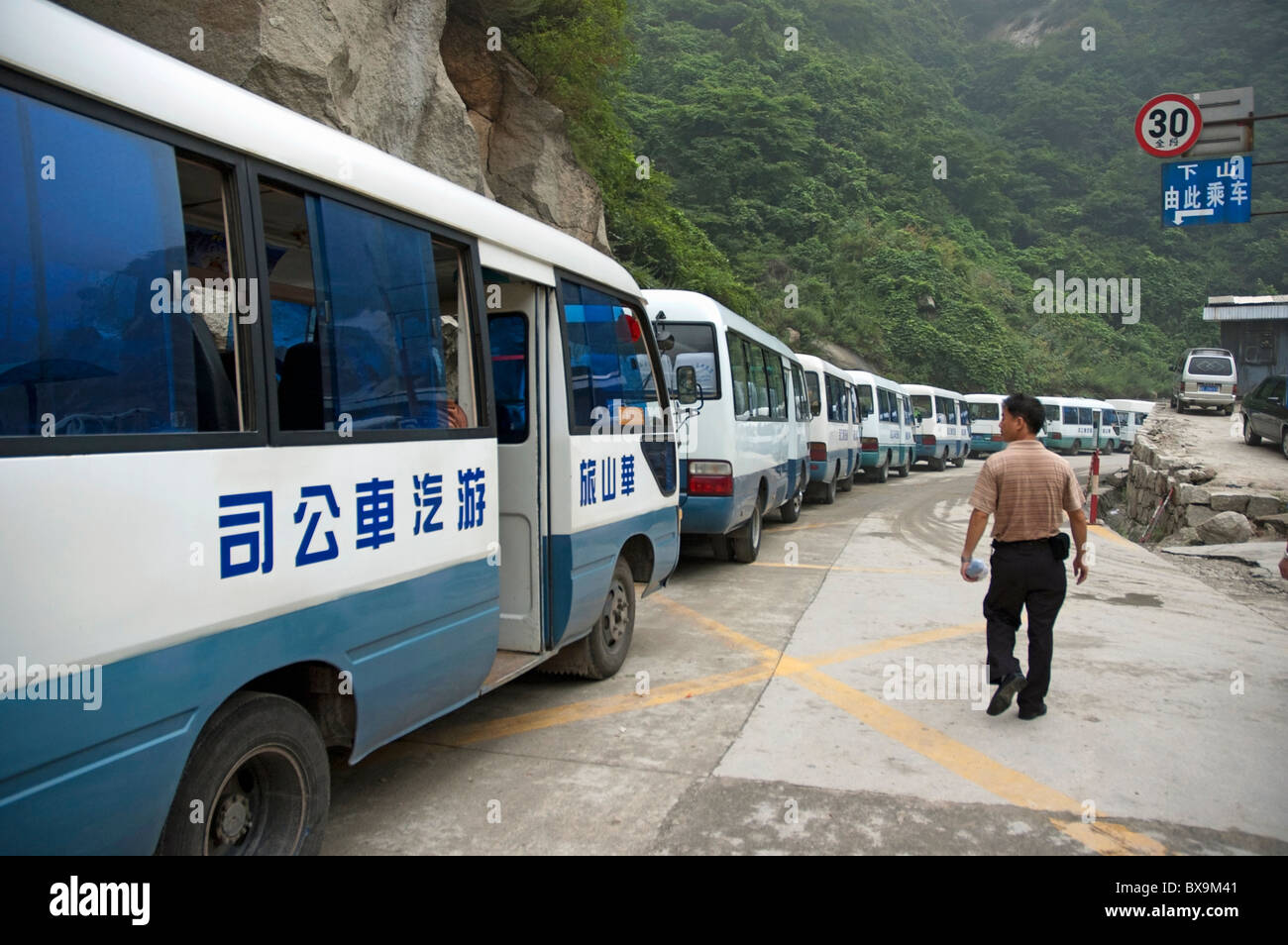 Mann auf der Suche unter einer Reihe von Touristenbusse parkten auf Mount Hua, einer von Chinas fünf heiligen taoistischen Berge, in Shaanxi, China. Stockfoto