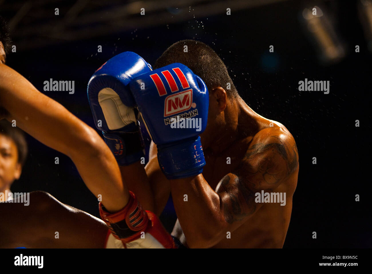 Asiatische Boxer mit Handschuhen erhalten Schlag auf Kopf senden Schweiß beim outdoor Amateur Muay thai kickboxen Spiel fliegen Stockfoto