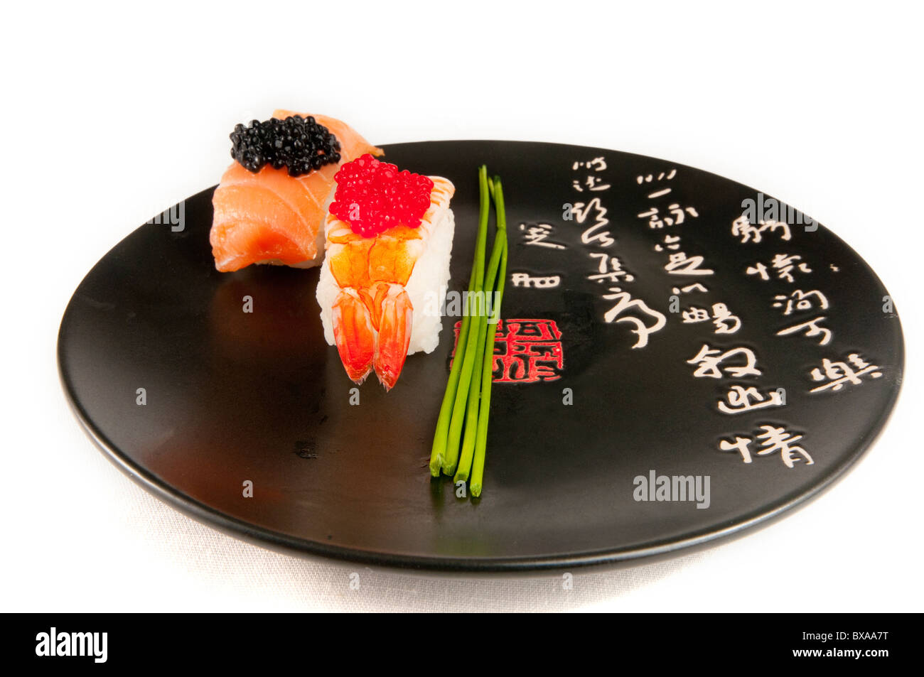 Nigiri Sushi mit Garnele, Fischeier und Lachs garniert mit Schnittlauch.  Auf einer schwarzen Platte mit dem japanischen schreiben in rot und weiß. Stockfoto
