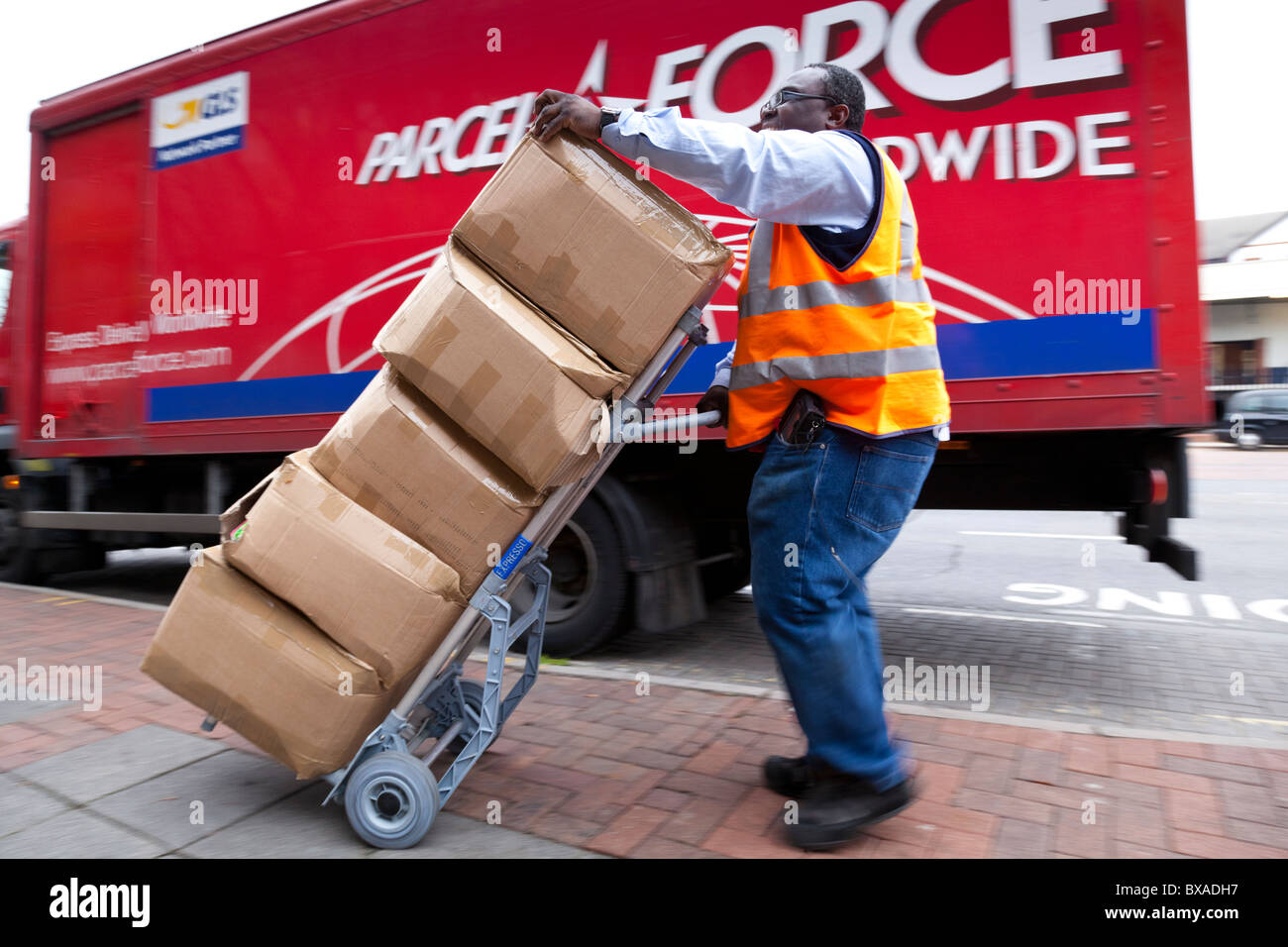 Ein Kurier verwendet einen Trolley, um schwere Pakete zu bewegen. Stockfoto