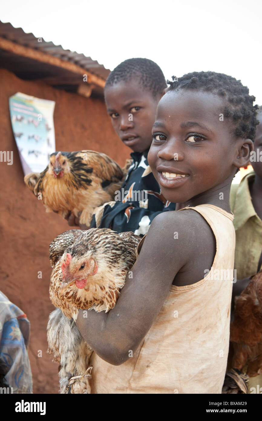 Kinder bringen ihre Hühner zu einem gemeinschaftlichen Impfung Tag in Nampikika Dorf, Iganga Bezirk, östlichen Uganda, Ostafrika. Stockfoto