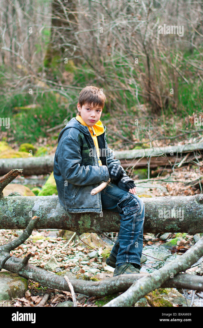 Der Junge saß auf einem Baumstamm im wilden Wald Stockfoto