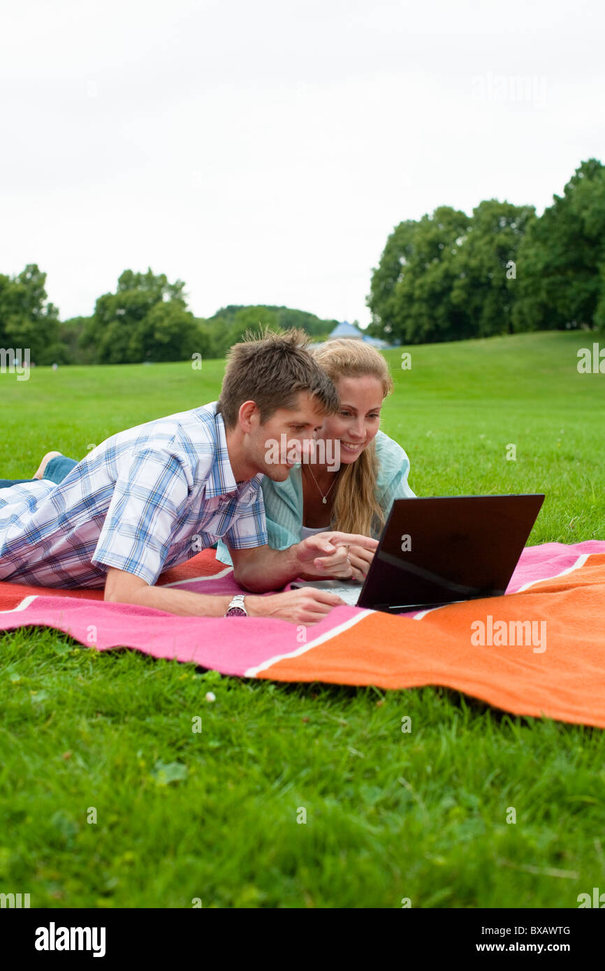 Mitte erwachsenes paar auf der Decke liegend und mit laptop Stockfoto