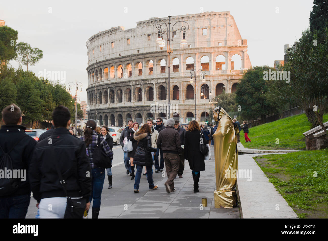 Roma, via dei Fori Imperiali mit Straßenkünstler und Passerbies, Kolosseum im Hintergrund. Stockfoto