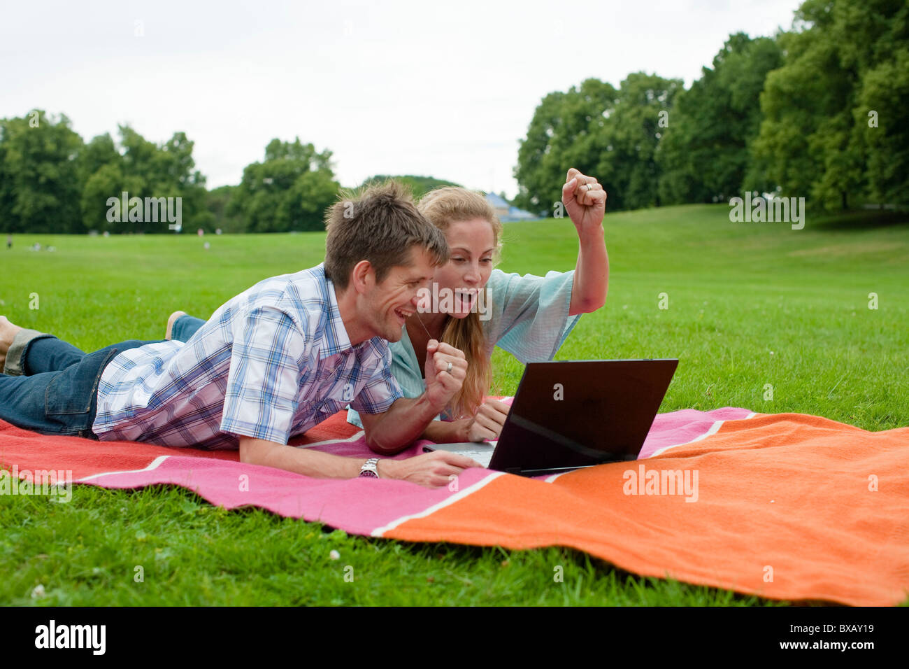 Glückliches Paar im Park liegen und mit laptop Stockfoto
