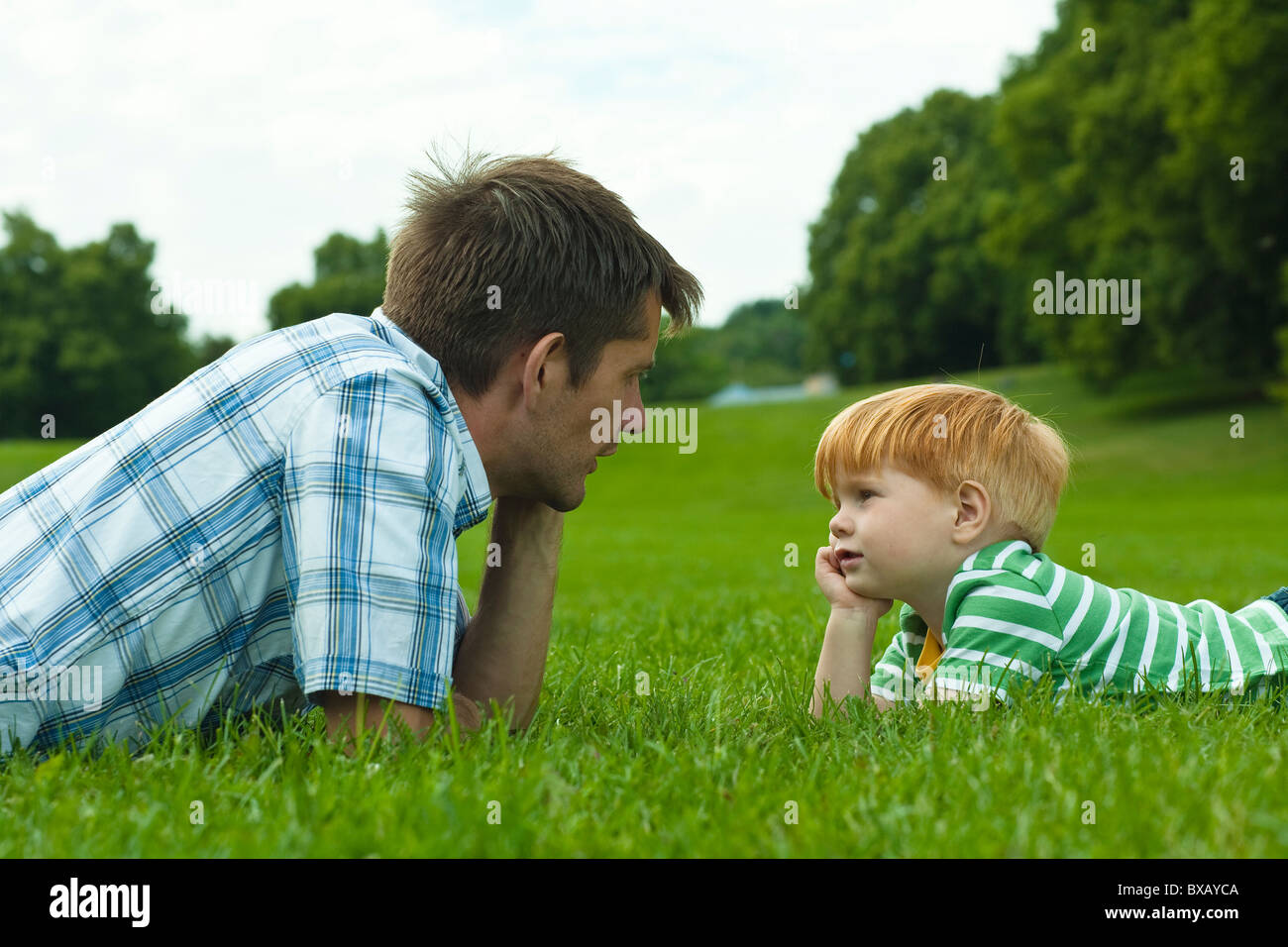 Vater und Sohn auf Rasen im Park liegen Stockfoto