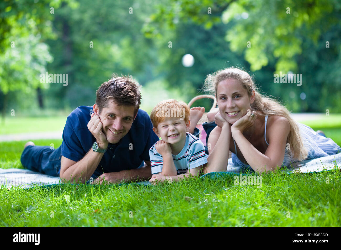 Eltern mit Sohn im Park liegen und Blick in die Kamera Stockfoto
