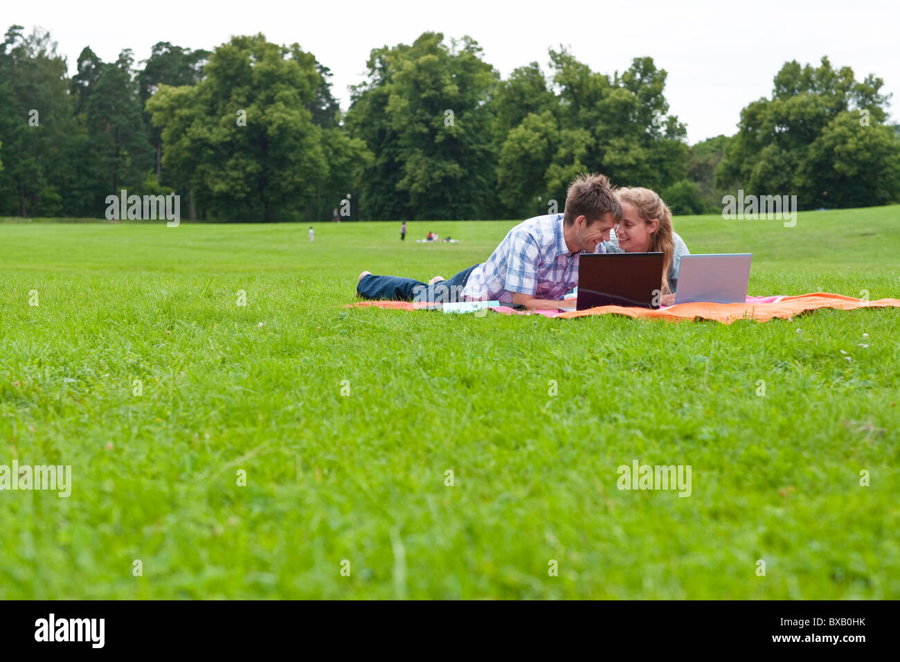 Mitte erwachsenes paar liegend auf einer Decke im Park mit laptops Stockfoto