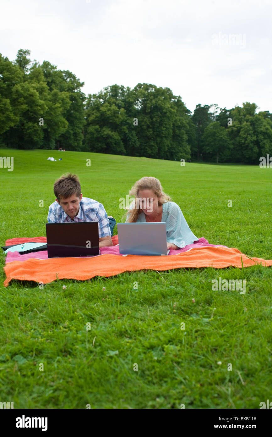 Mitte erwachsenes paar auf der Decke liegend und mit Notebooks Stockfoto