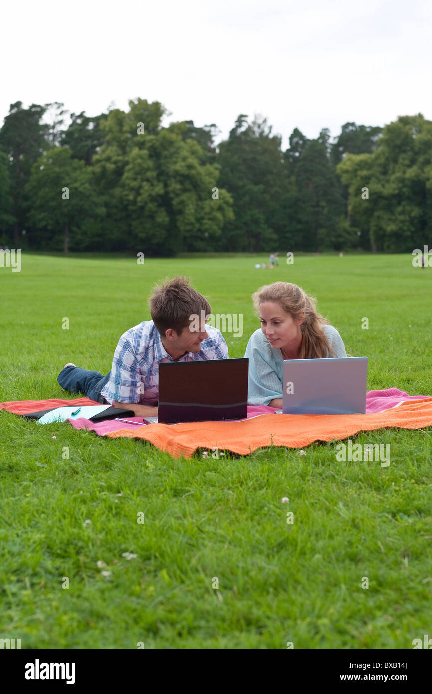 Mitte erwachsenes paar auf Decke im Park liegen und mit Notebooks Stockfoto
