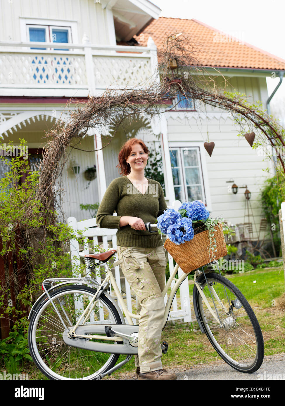 Frauen stehen mit Fahrrad vor Haus, Lächeln Stockfoto