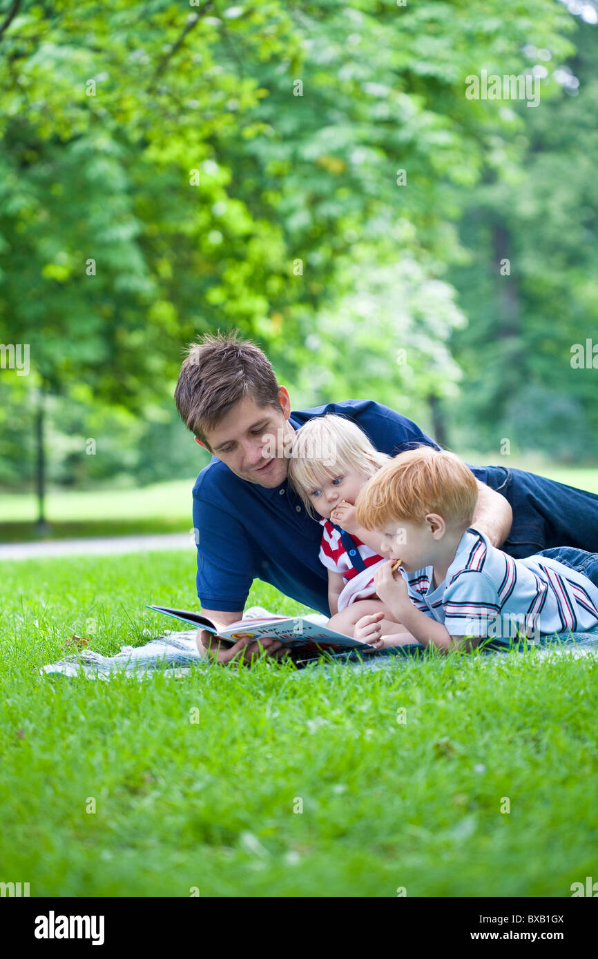 Lesebuch von Vater, Sohn und Tochter im park Stockfoto