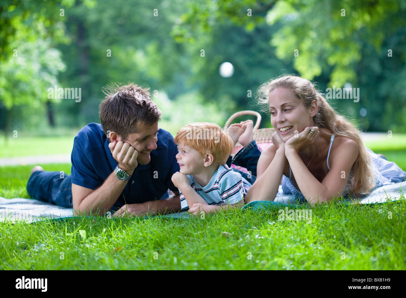 Eltern mit Sohn im Park liegen und wegsehen Stockfoto