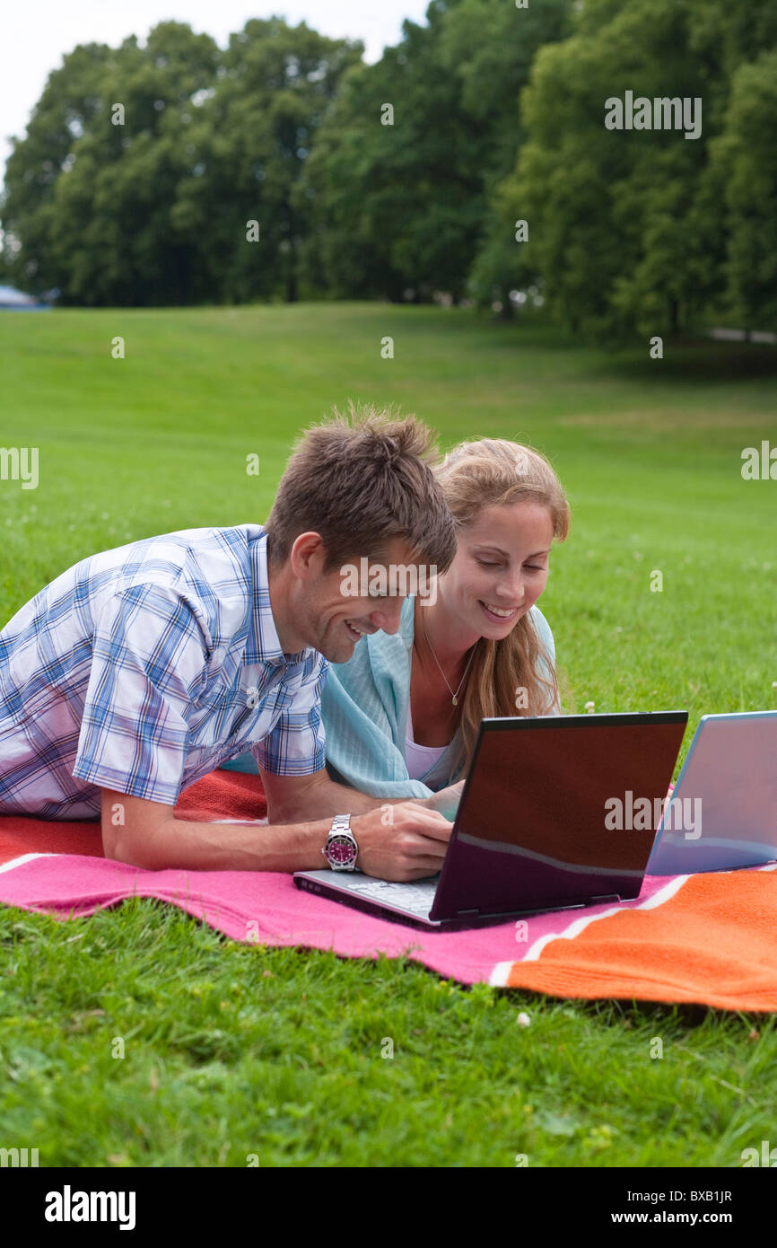 Mitte erwachsenes paar auf der Decke liegend mit Notebooks Stockfoto