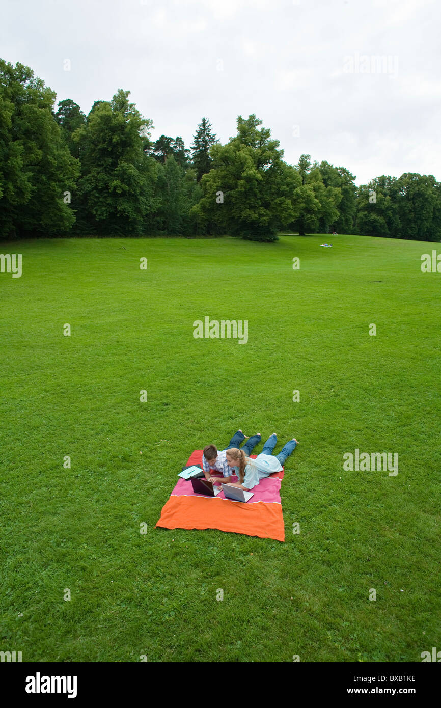 Paar mit Laptops auf Decke im Park liegen Stockfoto