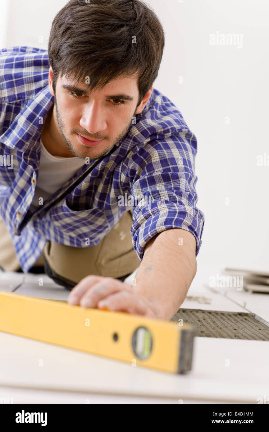 Home Fliesen Verbesserung - Handwerker mit Ebene Festlegung Fliesenboden Stockfoto