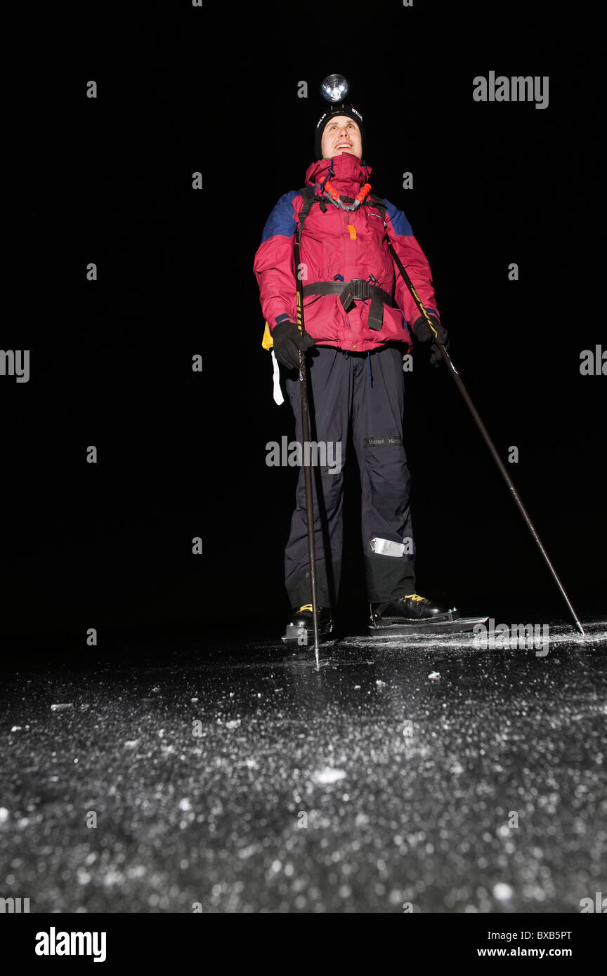 Mann trägt Schlittschuhe und Stirnlampe nachschlagen in der Nacht Stockfoto