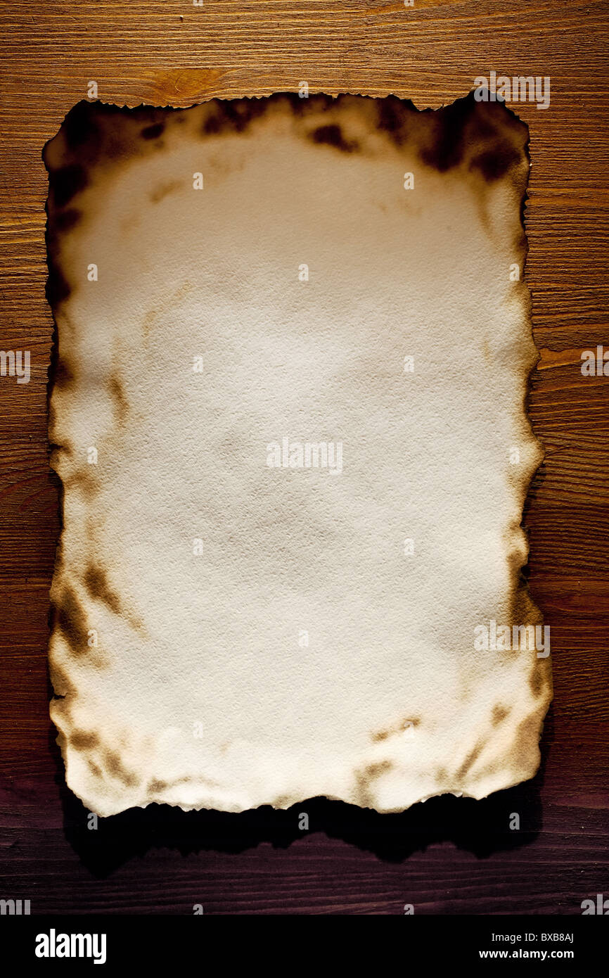 Auf den Kanten texturierte Papier gegen eine Holzwand verbrannt Stockfoto