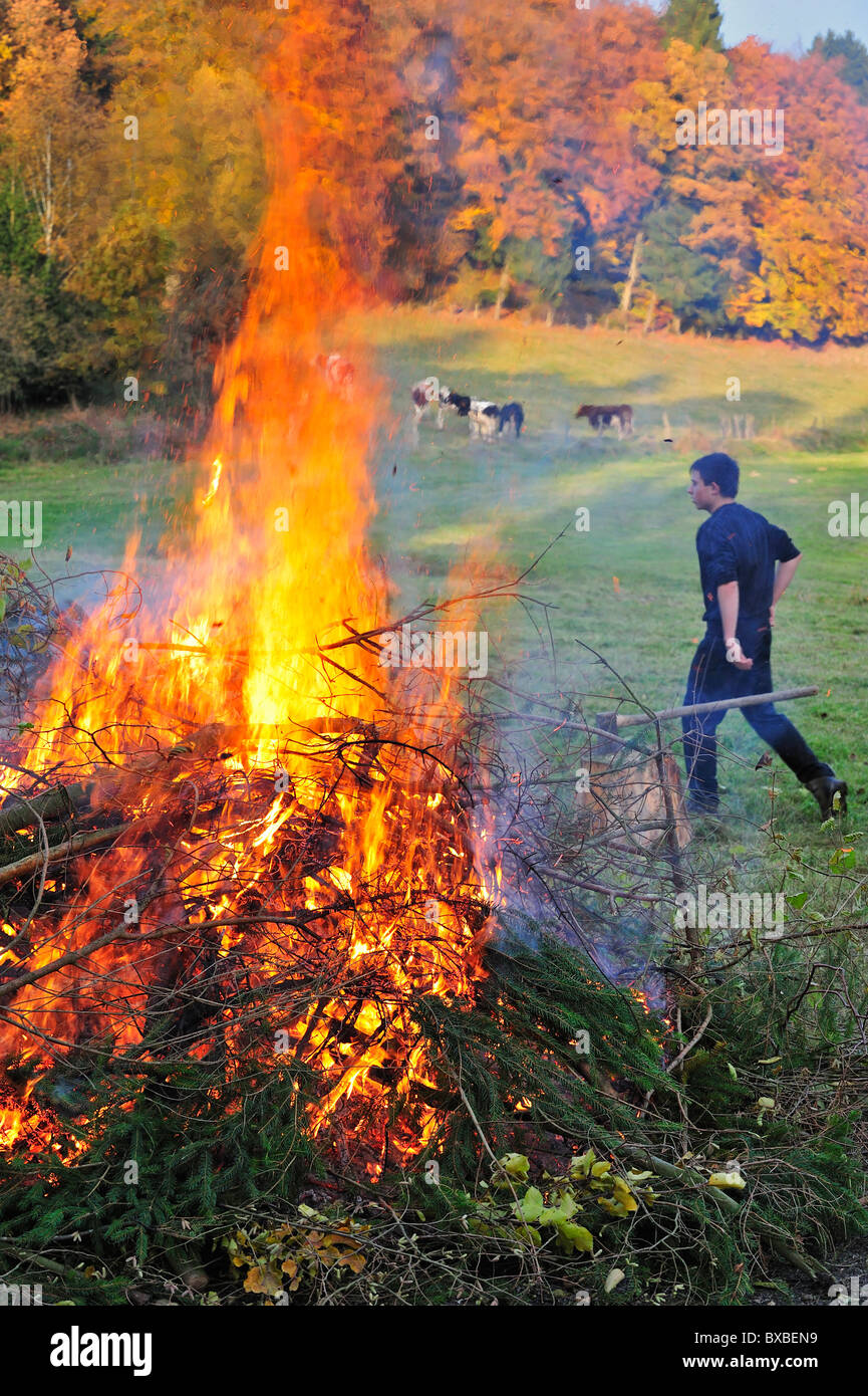 Junge riesige Feuer durch das Verbrennen von Beschneidungen / Drum und dran auf Bauernhof, Ardennen, Belgien Stockfoto