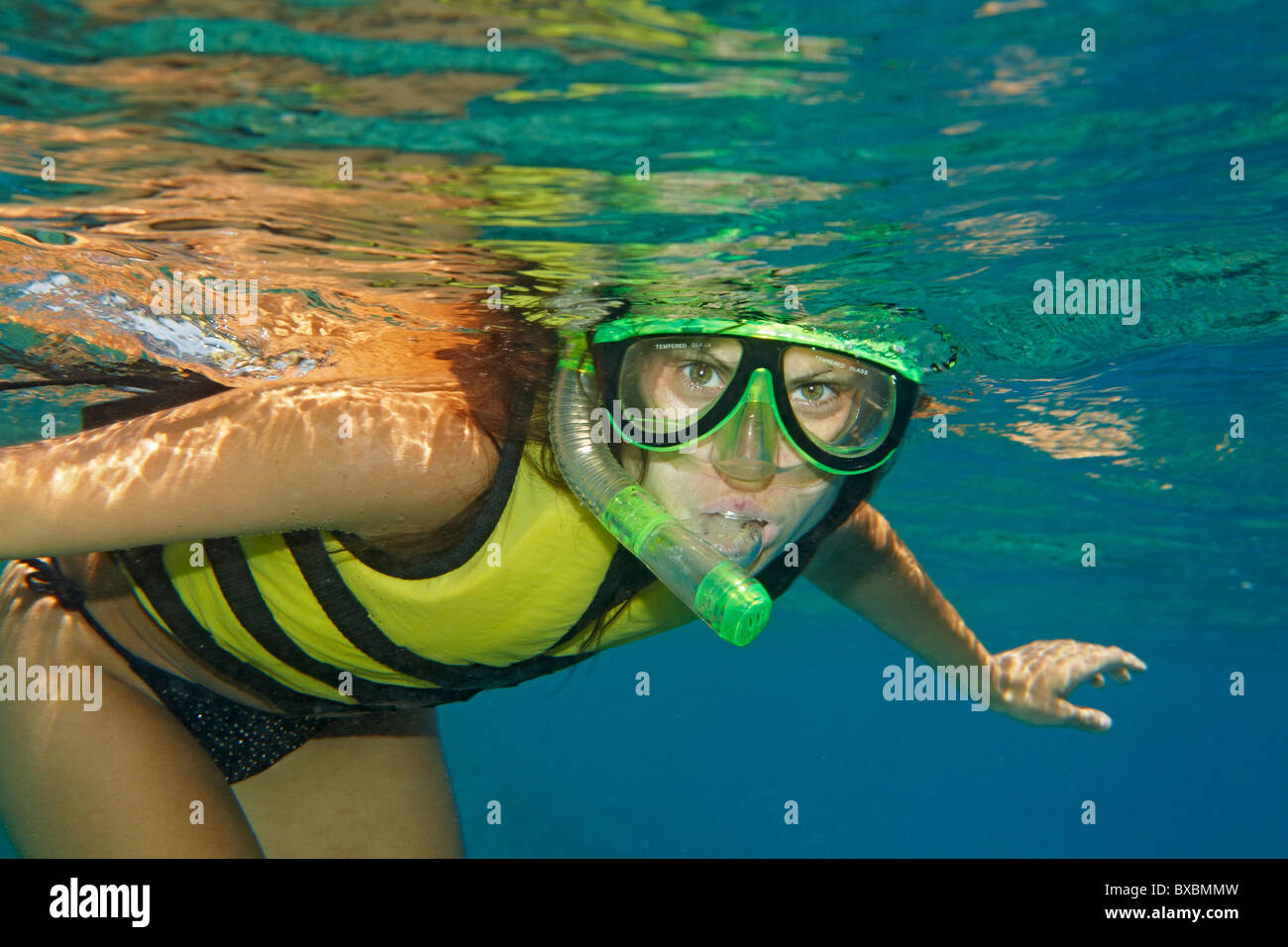 Frau Schnorcheln im Roten Meer - gelbe Schwimmweste, blaues Wasser, grüne Maske Stockfoto
