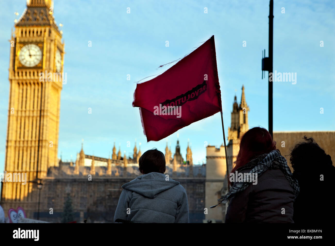 Demonstranten halten oben eine rote Fahne Flagge 'Revolution' im Unterricht Gebühren Protest in Parliament Square, London. Stockfoto