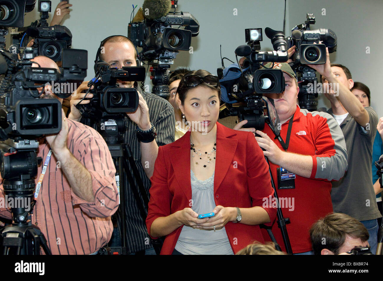 Asiatisch-amerikanische weibliche Nachrichten Reporter Tweets aktuelle Nachrichten auf ihr Handy zu aktualisieren, während der Pressekonferenz in Austin, Texas Stockfoto