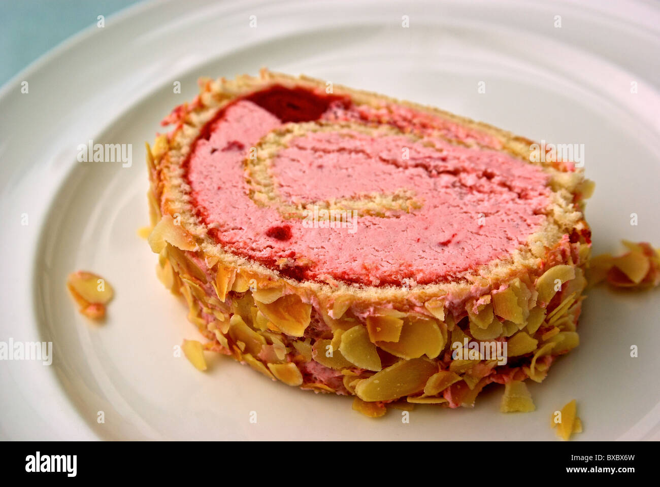 Erdbeer Eis Kuchen Roll bedeckt in gerösteten Mandelsplitter dessert Stockfoto