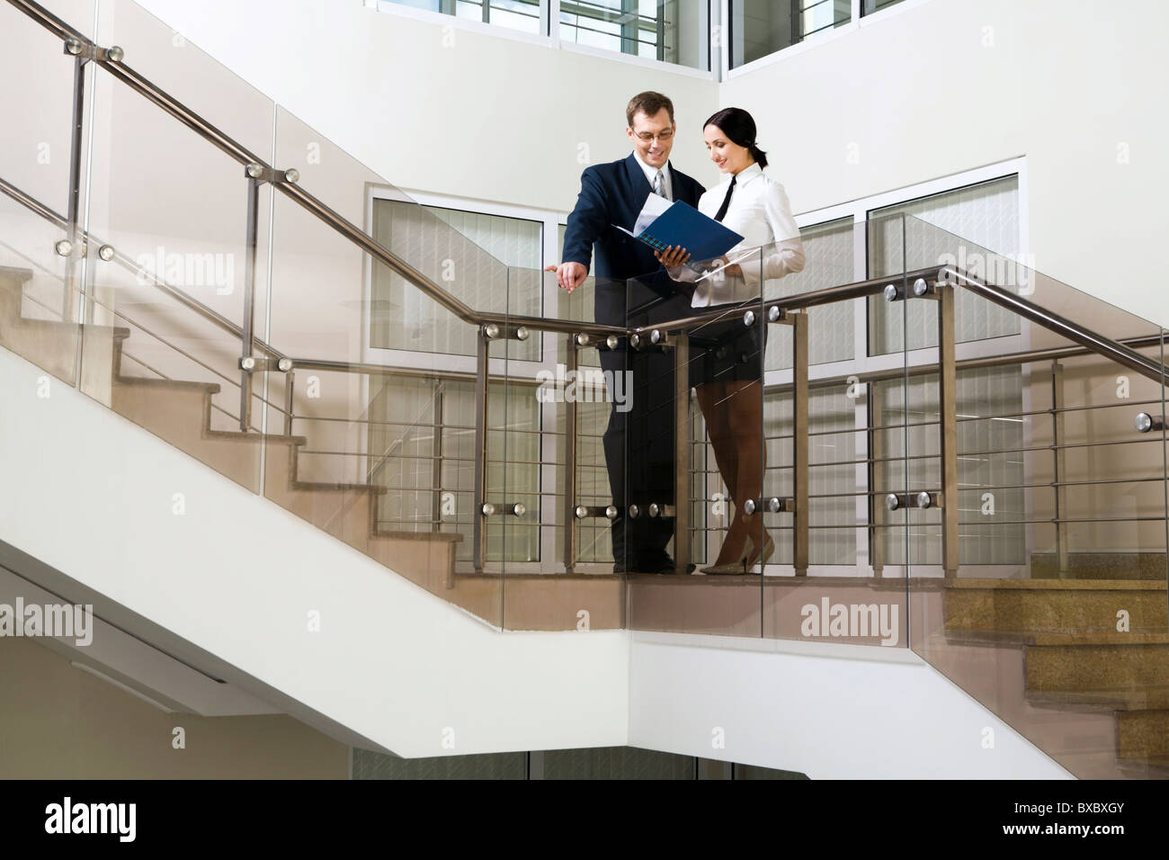 Junge süße hispanischen Geschäftsfrau zeigt Dokumente an ihre Kollegen auf Treppe im Bürogebäude Stockfoto