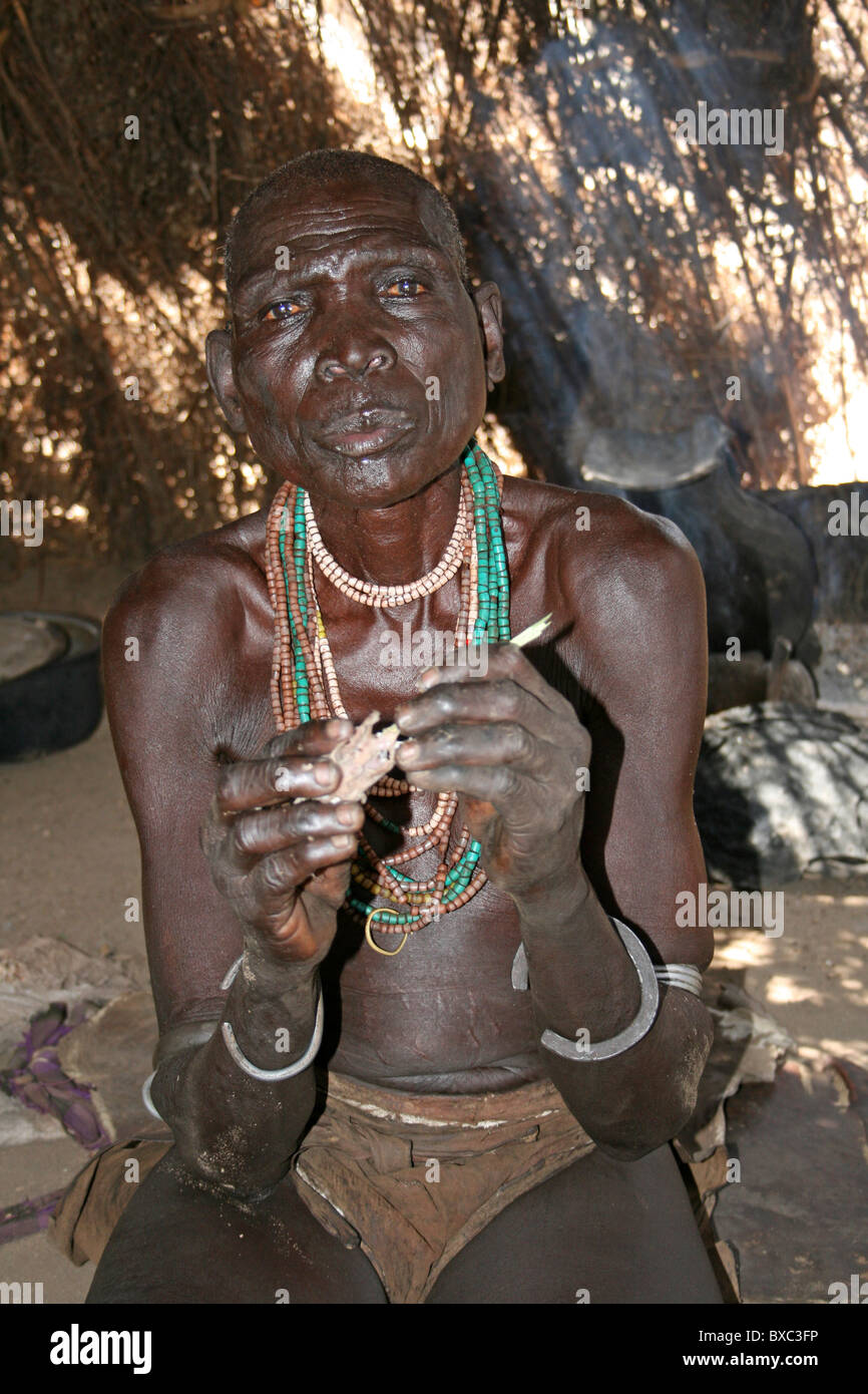 Ältere Karo Stamm Frau Essen Knochenmark In ihrer Hütte, Omo-Tal, Äthiopien Stockfoto