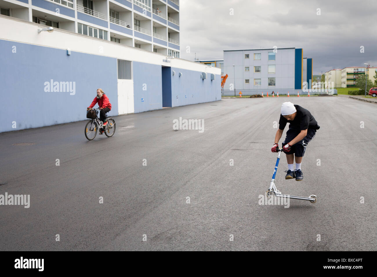 Junge auf einem Roller außerhalb Wohnung Blöcke springen. Hafnarfjordur, größere Fläche, Island Stockfoto