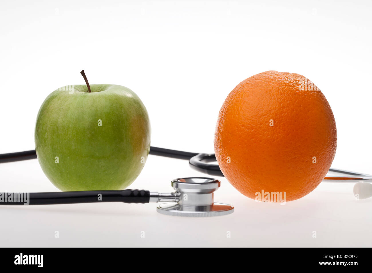 Einen Apfel und eine Orange, eingewickelt in ein Stethoskop auf weißem Hintergrund Stockfoto