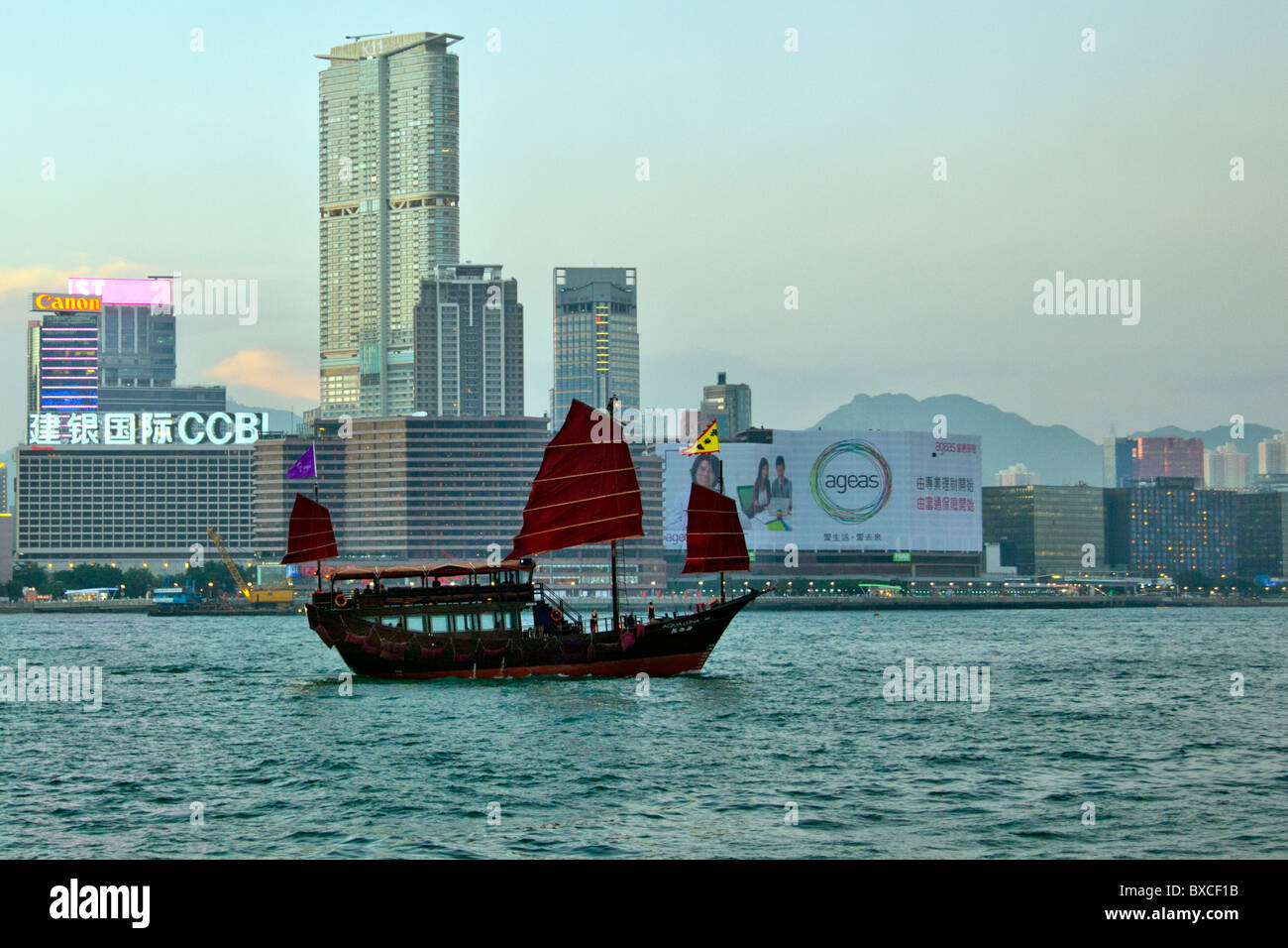 Hong Kong Junk-Fahrten auf Victoria Harbour, Hafen, mit Kowloon im Hintergrund rote Fledermausflügel Segel iconic Anblick Stockfoto