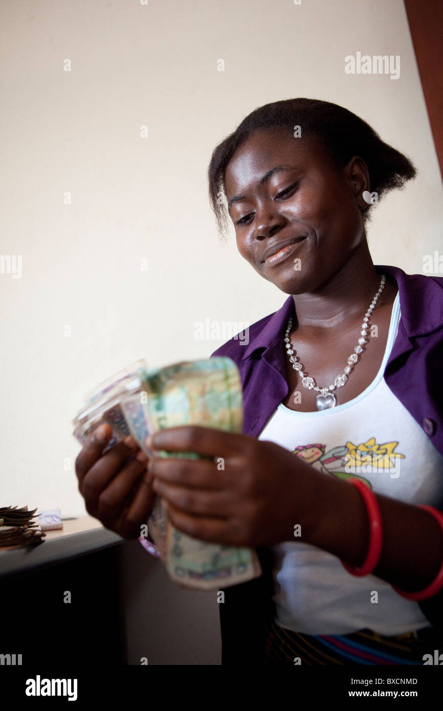 Eine Frau zählt Geld nach Erhalt eines Mikrofinanz-Darlehens in Freetown, Sierra Leone, Westafrika. Stockfoto