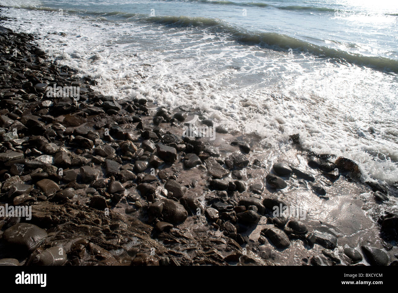 Schimmernden Wellen an einem steinigen Strand Stockfoto