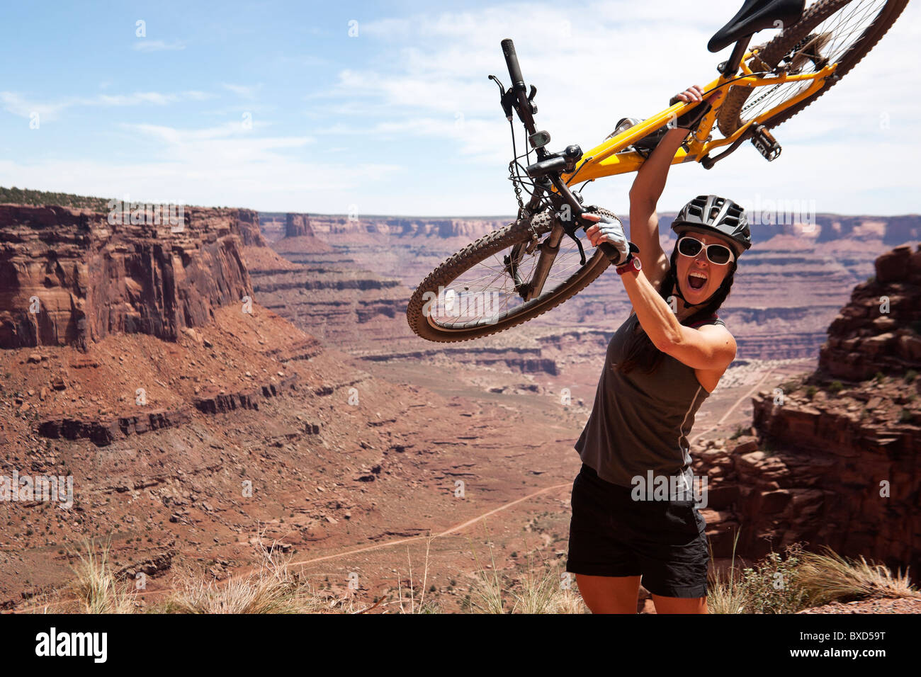 Eine Frau hoch halten Sie ihr Fahrrad mit Schluchten in der Ferne. Stockfoto