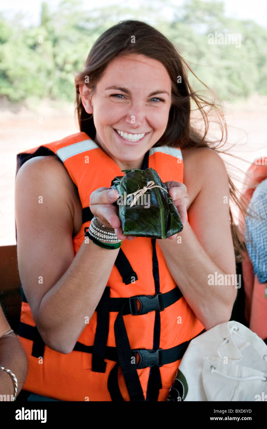 Eine junge Frau hält Mittagessen für den Tag: Reis und Gemüse eingewickelt in ein Blatt, auf dem Amazonas. Stockfoto